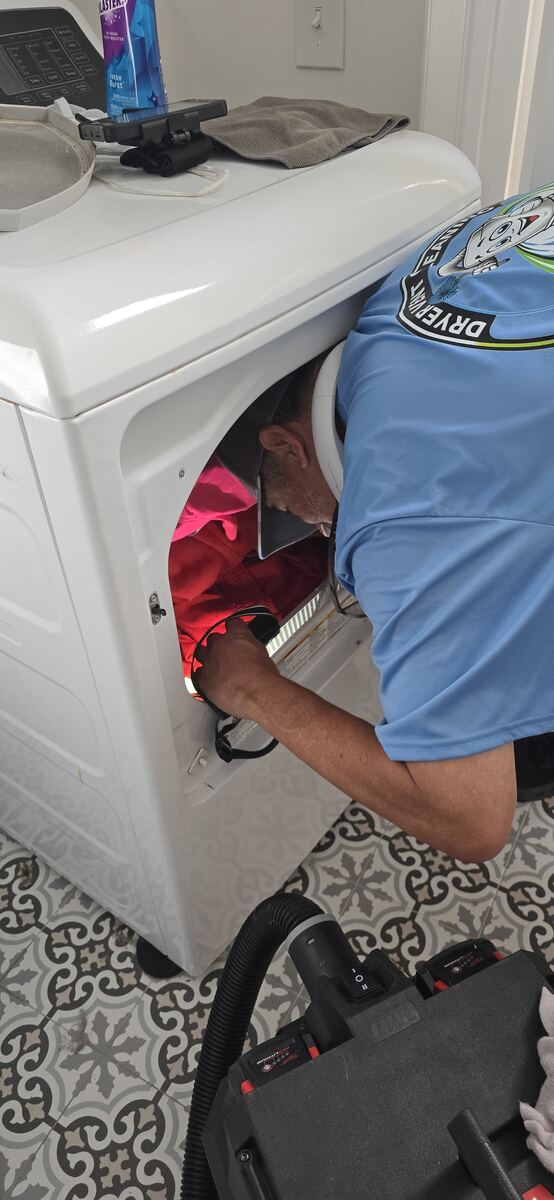 Technician deep-cleaning lint from inside the dryer cabinet